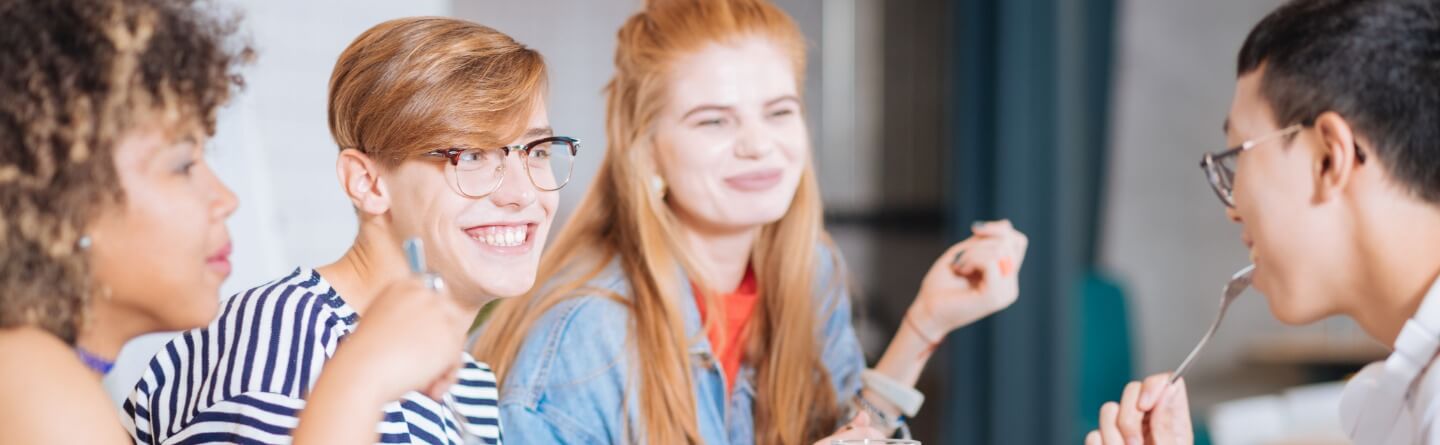 Headerbild: Vier Personen unterhalten sich entspannt beim Essen