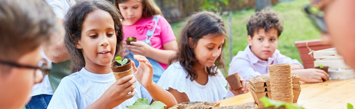 Headerbild: Gruppe junger Schüler*innen beim Eintopfen von Sprösslingen