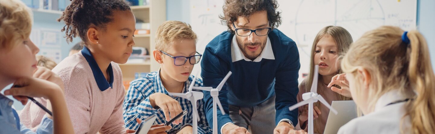 Headerbild: Schüler*innen und Lehrer bauen mit ihrem Lehrer ein Mini-Windrad 