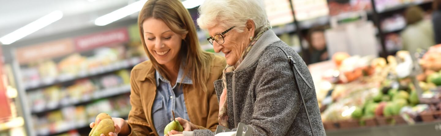 Headerbild: Seniorin und junge Frau am Obststand im Supermarkt